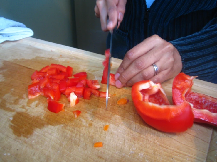 a woman slices up a tomato on a wooden  board