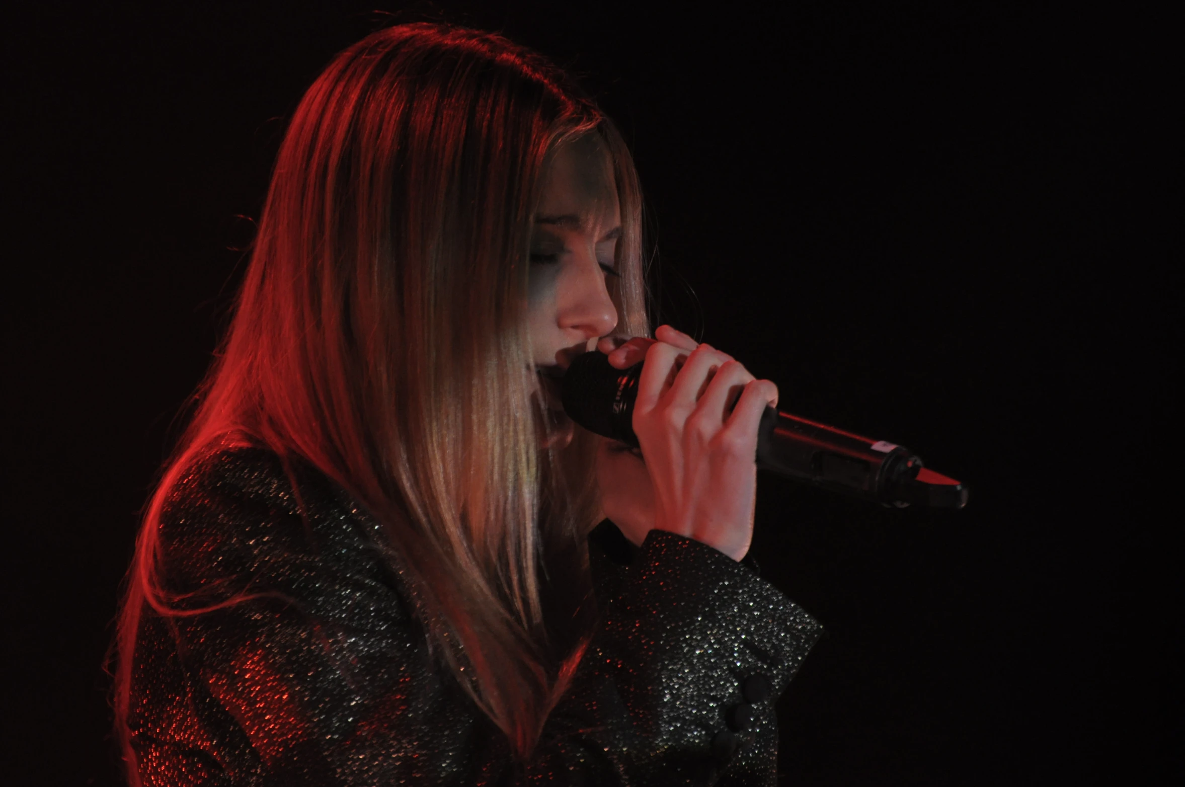 a woman with long hair singing into a microphone