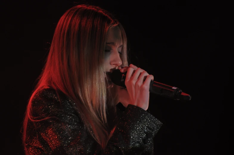 a woman with long hair singing into a microphone