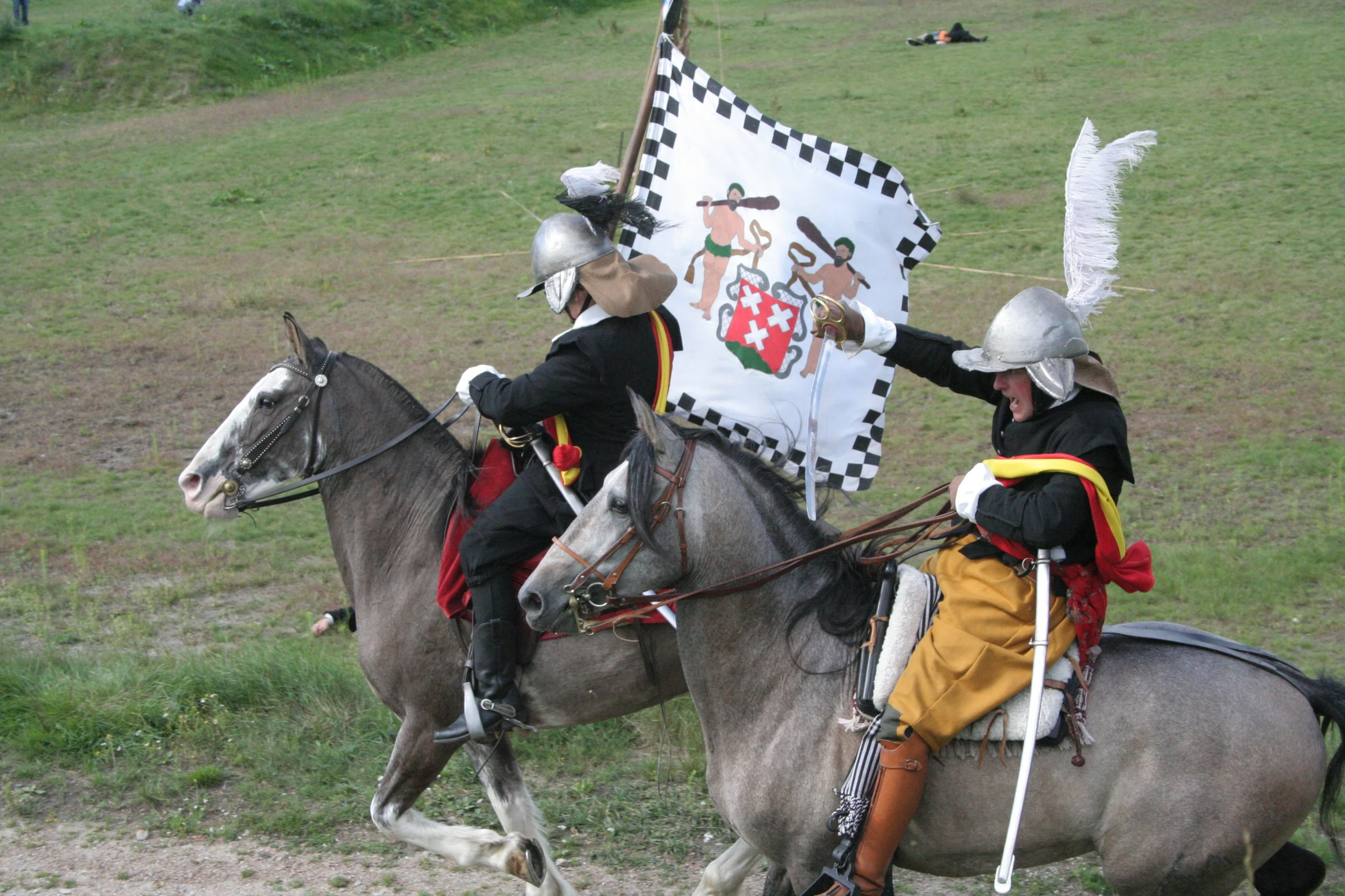 a couple of men are riding on horses in front of a flag