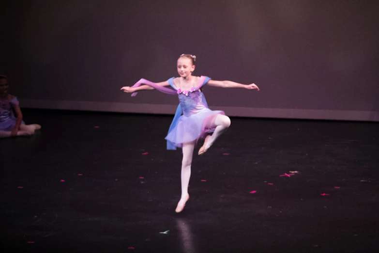 a young ballerina is doing tricks on the stage