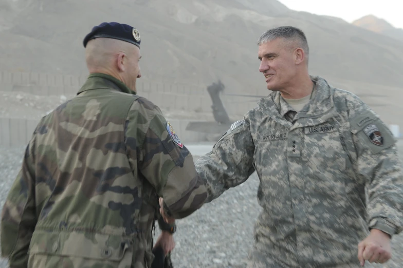 a couple of men shaking hands near a hill