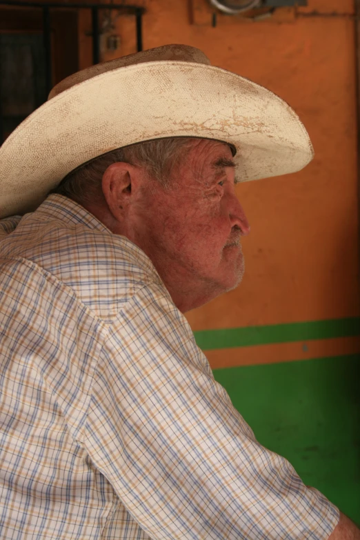 a man wearing a cowboy hat sitting on the back of a green bus