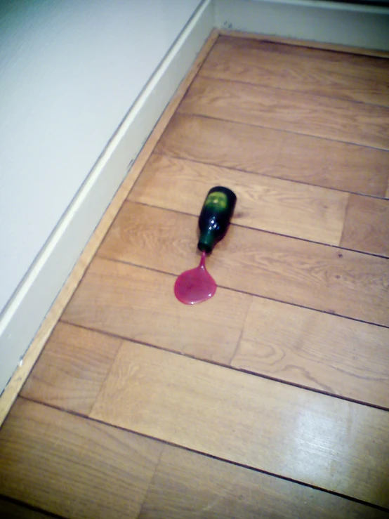 a wine bottle with a liquid drop on the floor