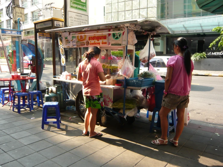 a couple of people standing at a table by a street