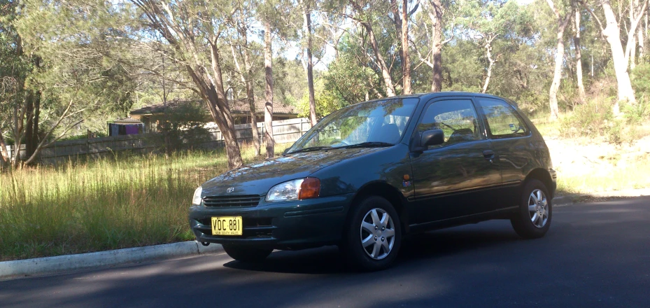 a grey car is parked on a wooded road