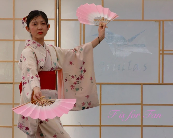 a woman in a kimono carrying pink umbrellas