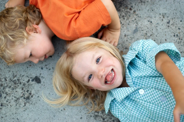 two children laying down smiling at the camera