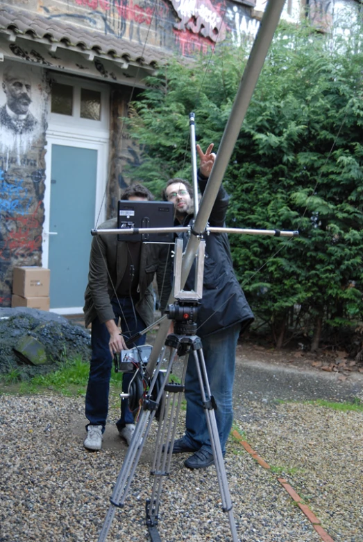 a man standing by a video camera holding a small device