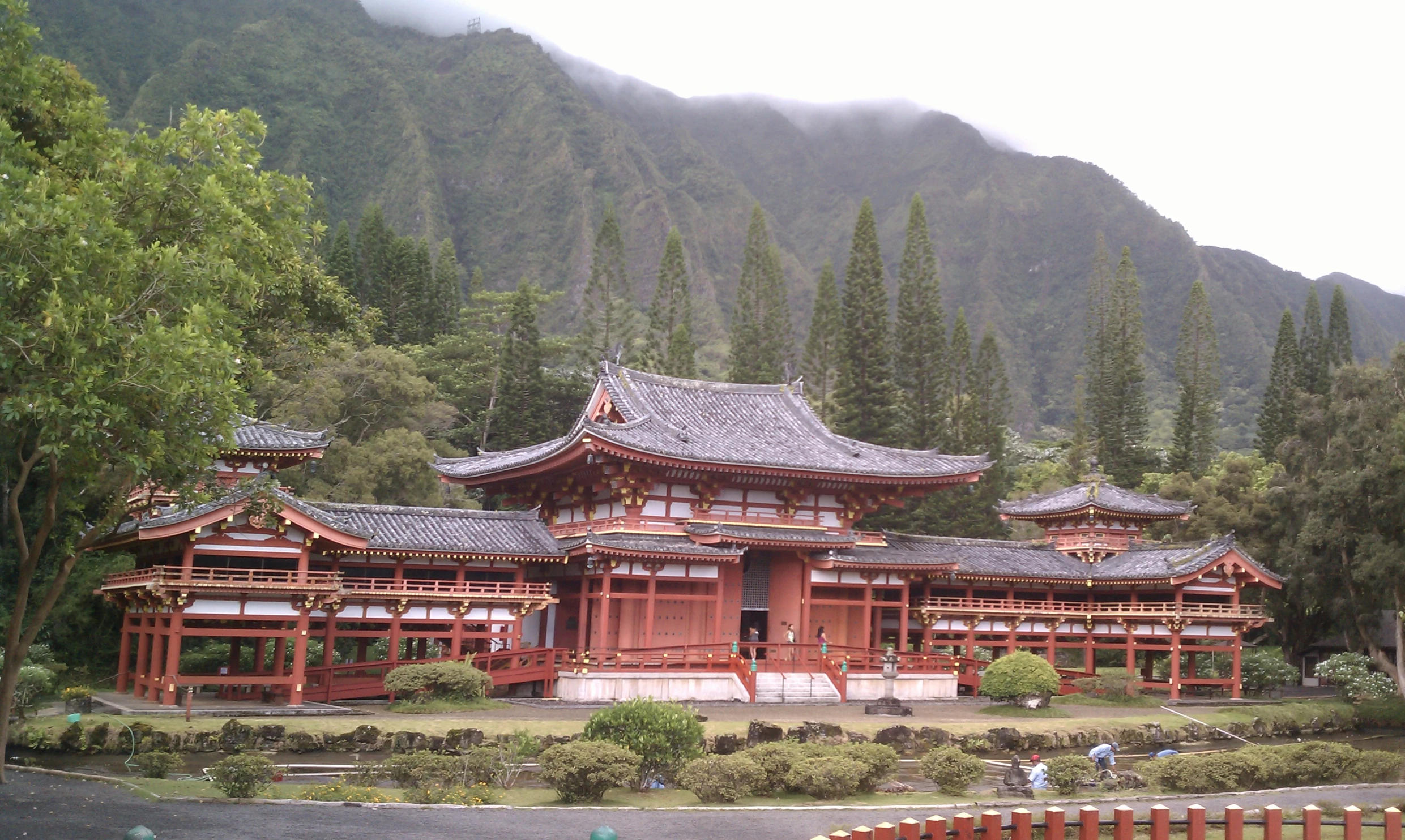 a wooden building in front of a lush green hillside