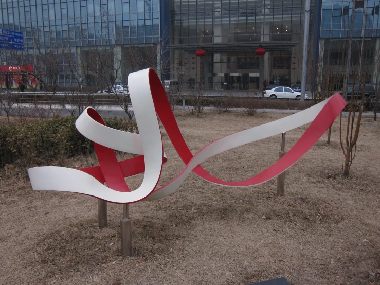 two white and red sculptures in front of a large building