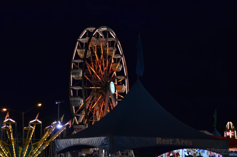 a carnival has ferris wheel lit up and several lights on