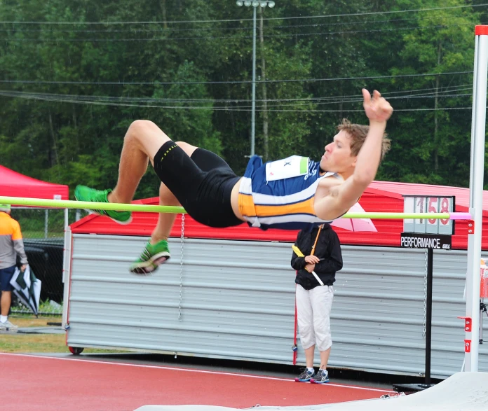 the boy is jumping to the high jump on his knees