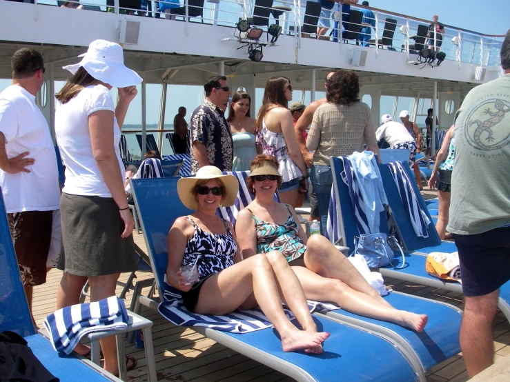 a crowd of people stand and sit on deck chairs