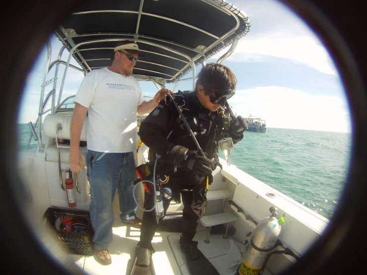 man holding scuba equipment standing on the deck of a boat