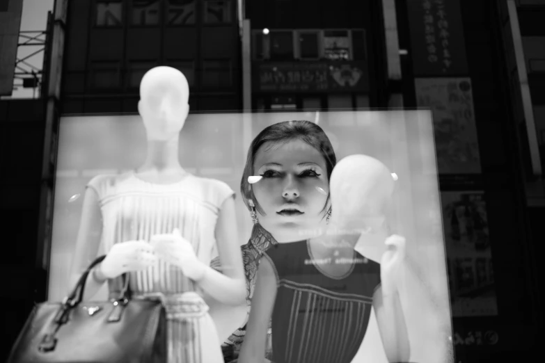 two women in dresses standing behind a display of mannequins