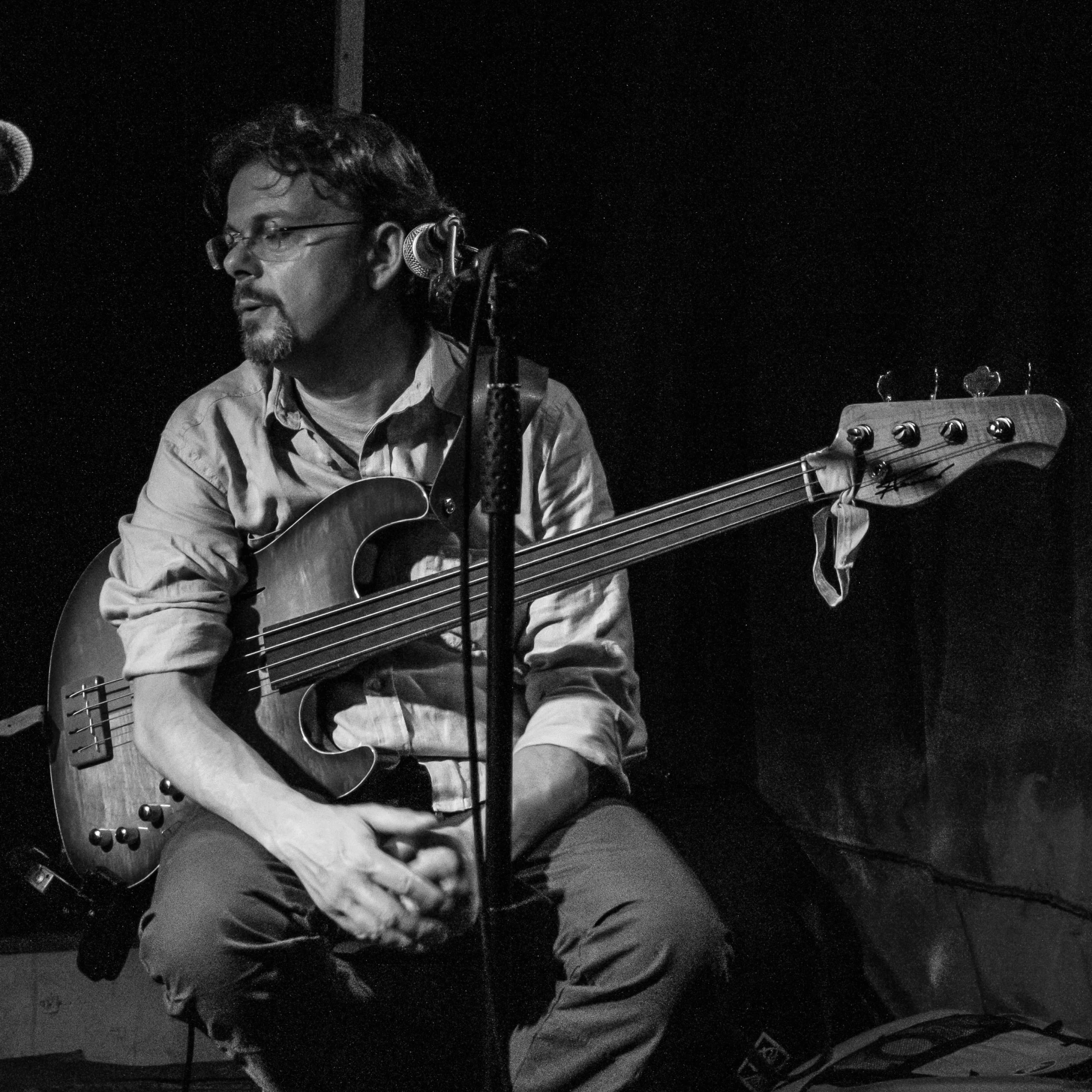 man sitting down while playing bass guitar