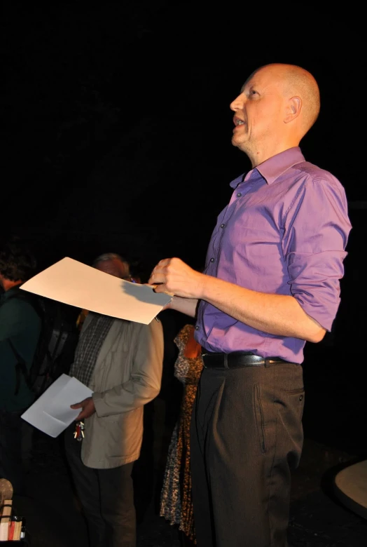 a man holds papers while speaking to people