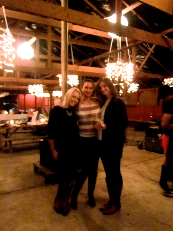 three women are standing in a building with chandelier lights