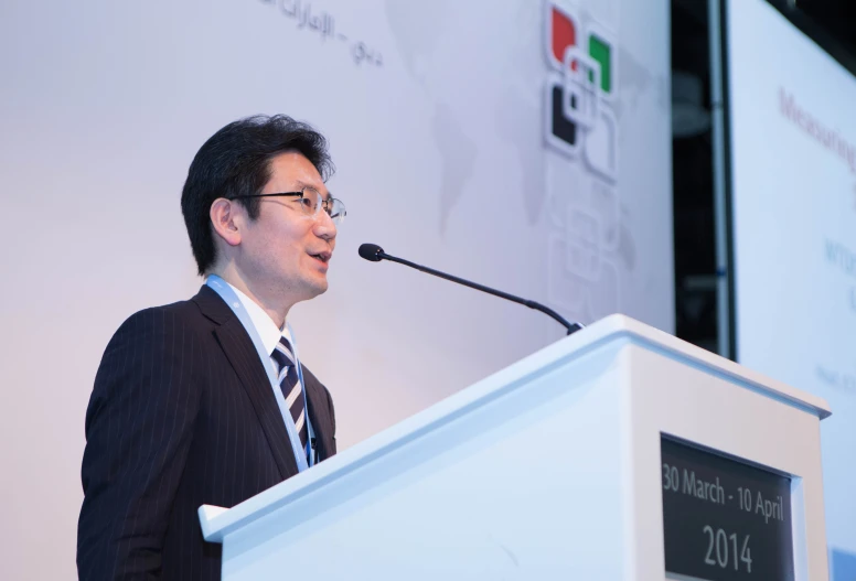 man in glasses speaking from behind a lectern