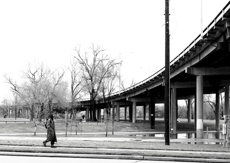 a woman walking down a street next to a bridge