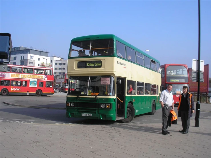 two people standing in front of a double decked bus