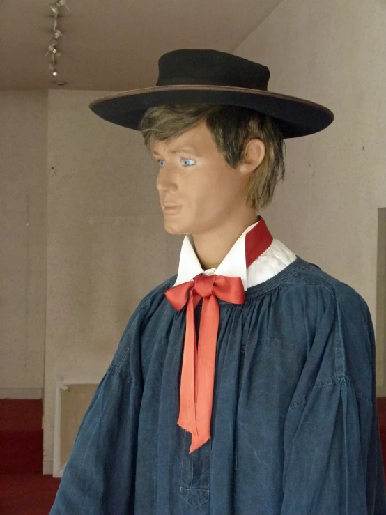 there is a mannequin dressed in a robe, hat, and orange tie