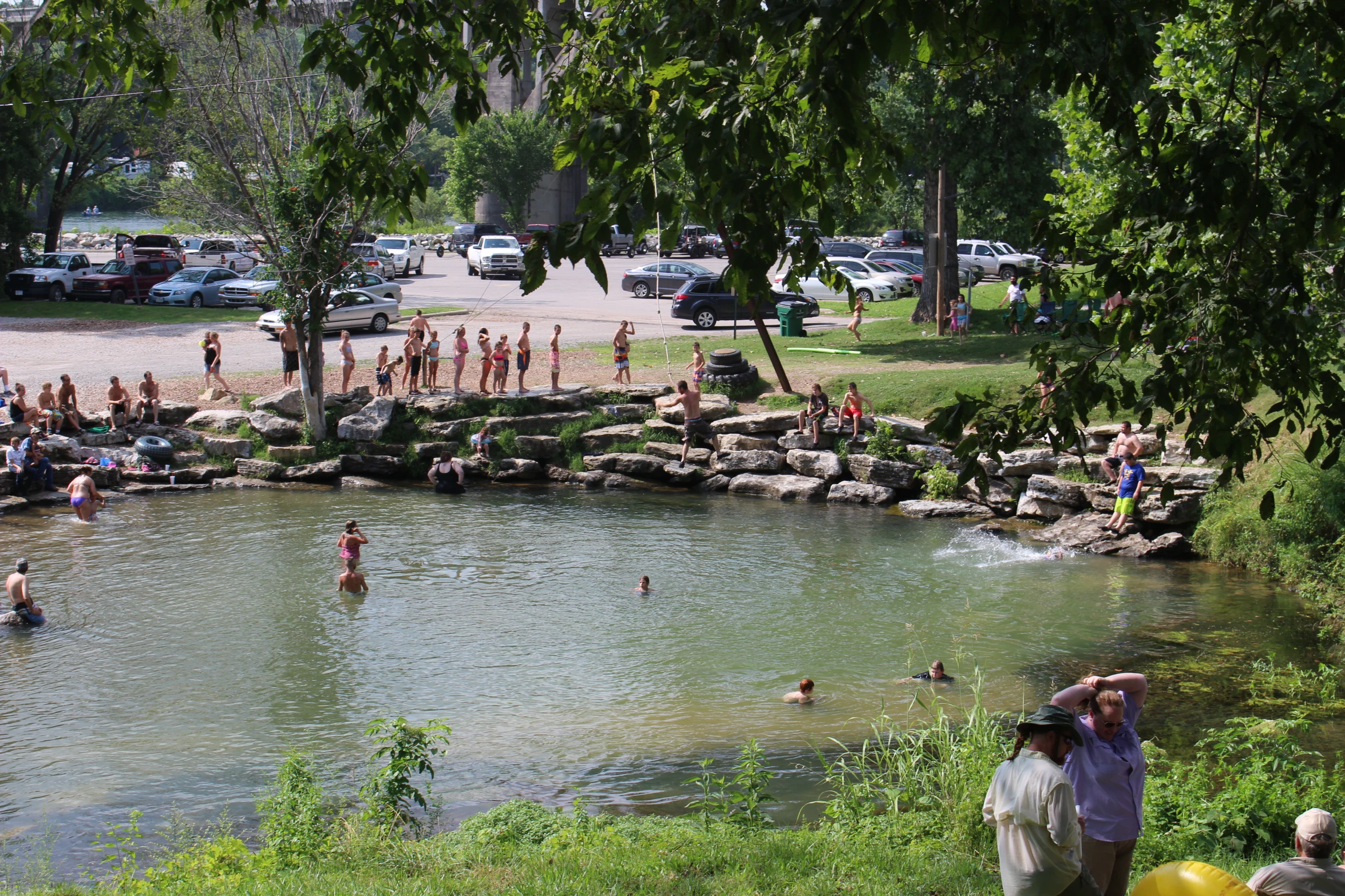 a large pond filled with lots of people surrounded by trees