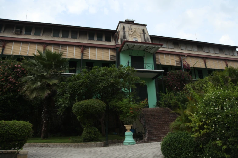 the outside of a multi - story building with bushes around the courtyard and front walkway