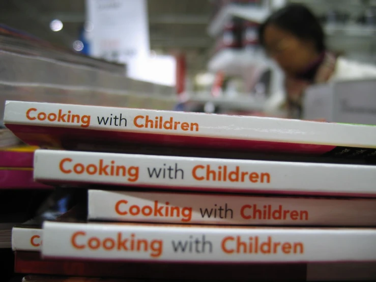 a stack of cook books with an individual in the background