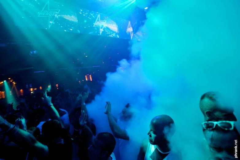 a group of people stand near an audience in front of blue smoke