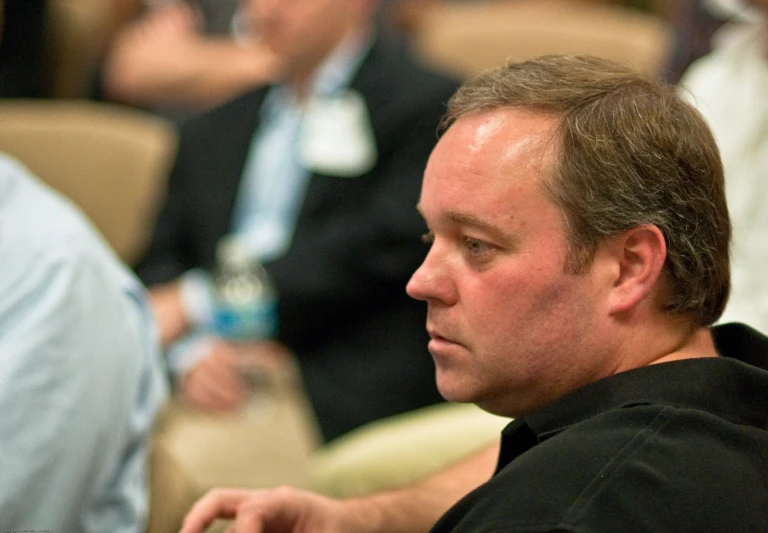 man in black shirt and blue shirt looking to his left