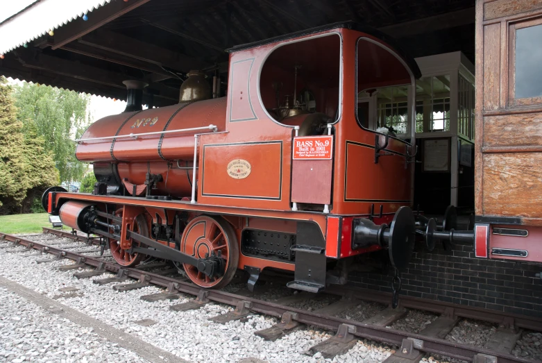 an old red and black train parked under a roof