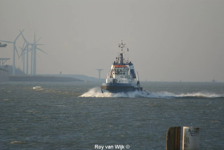 a small boat traveling through the water with windmills in the background