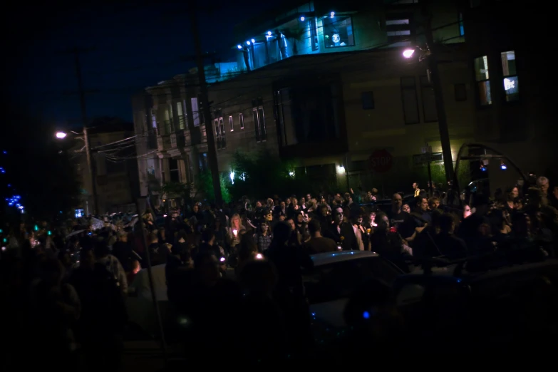 the crowd is gathered outside in front of some houses at night
