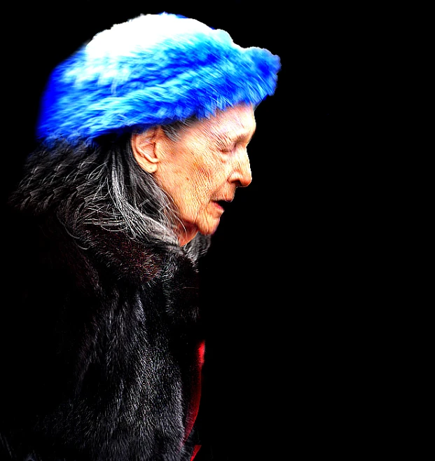 the woman is dressed in black with a blue fur hat