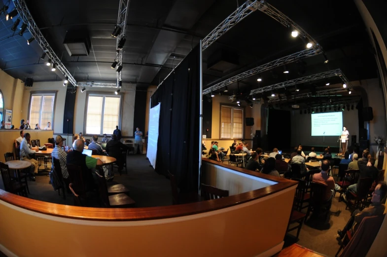 a group of people sitting at tables in front of projection screen