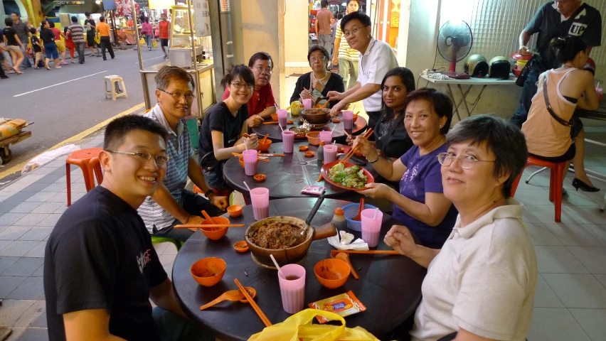 many people sit down together at a large table eating food