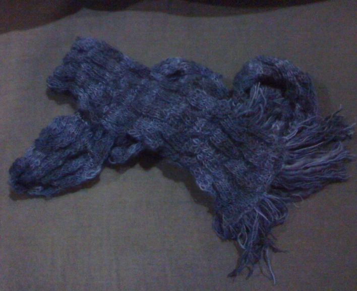 a knitted gray piece of material sitting on top of a bed