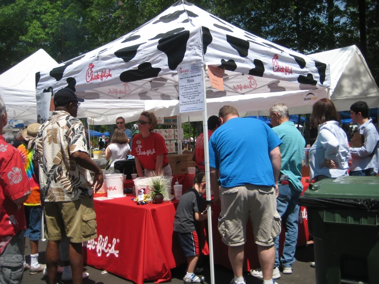 a group of people standing around a table under a tent