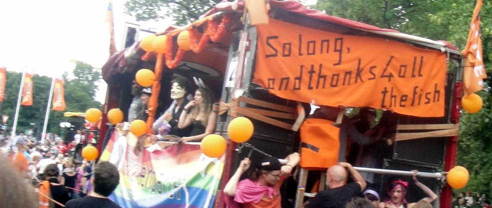 a crowd of people standing around in front of an orange and black truck