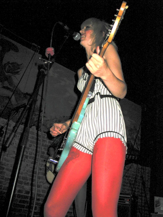 a girl in short leg pants playing an electric guitar