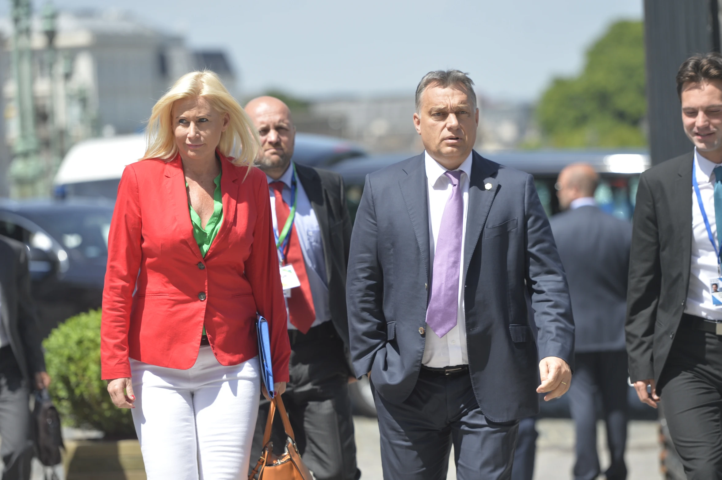 a woman in a red top is walking with a man and woman