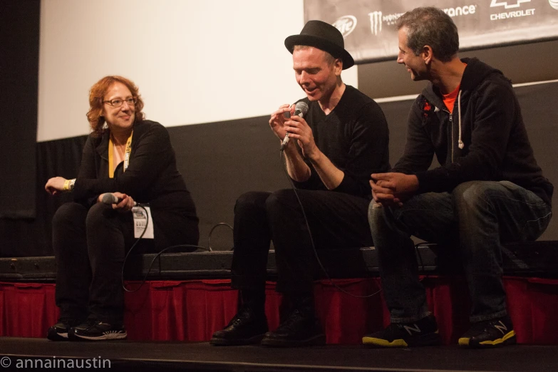 two men and a woman sitting on a stage