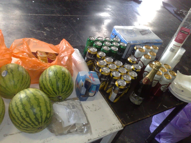 there are many sodas, watermelon, and soda cans on the table