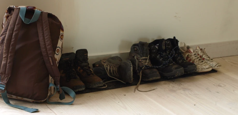 a group of shoes on the floor next to a backpack