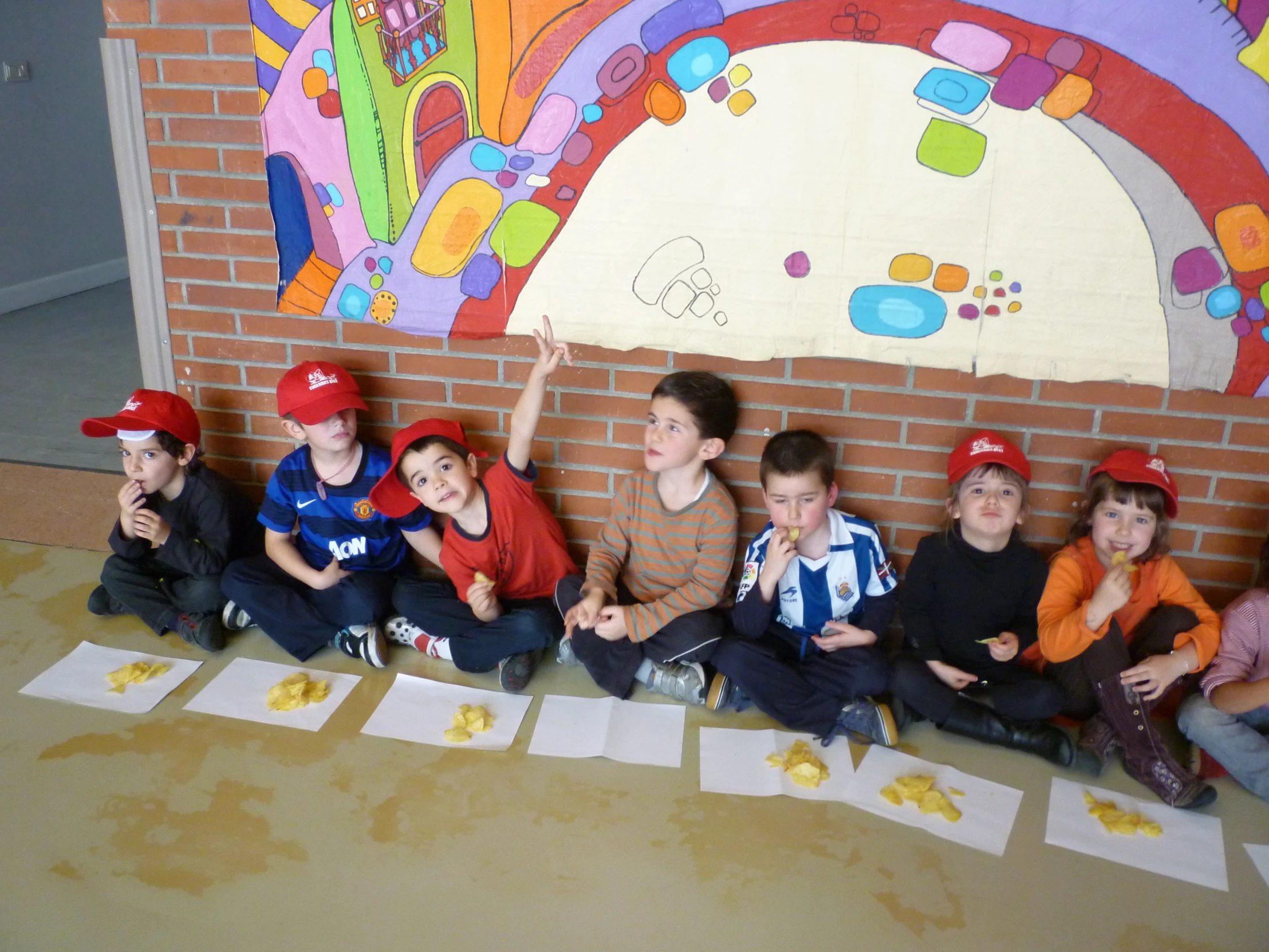 children posing for a picture while one child points at pictures on the wall