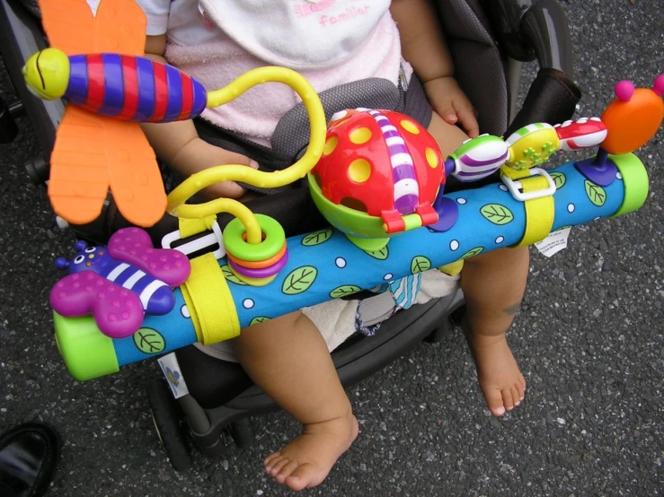 a small child in a stroller with some toys