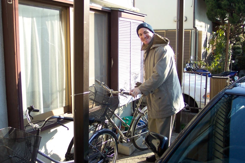 a man smiles while leaning on a bicycle in a house