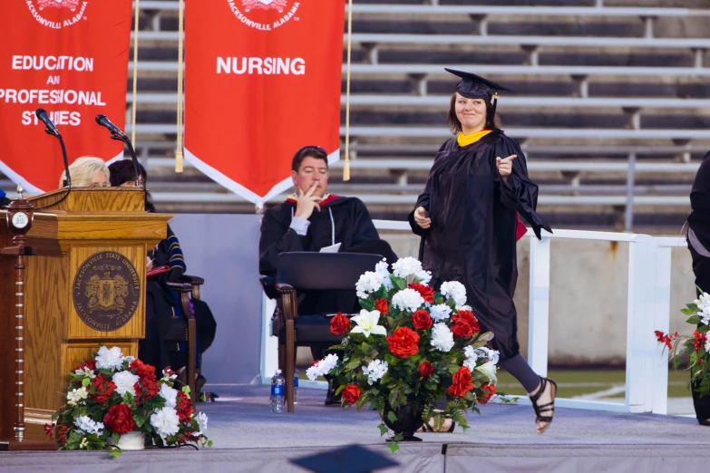 the graduate walks in front of several red banners